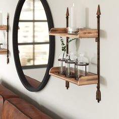 a mirror and shelf with candles on it in front of a wall mounted candle holder