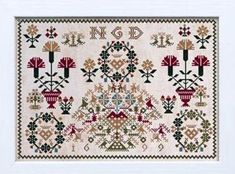 a cross - stitch pattern with flowers and trees on the front, in white frame