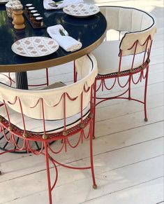 the table is set with four chairs and plates on it's legs, along with place settings