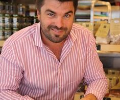 a man sitting at a table with a plate of food in front of him and smiling