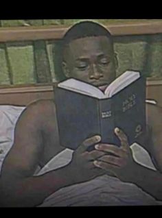 a man laying in bed reading a book