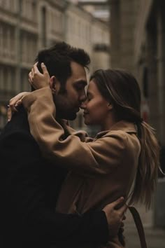 black and white photograph of a man kissing a woman's forehead on the street