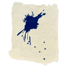 a piece of paper with blue ink splattered on it and the shape of a face