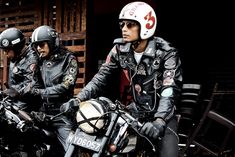 three men in leather jackets and helmets sitting on motorcycles