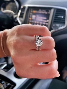 a woman's hand with a ring on it and a car steering wheel in the background