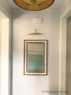 a painting hangs on the wall next to a doorway with a mirror and light fixture