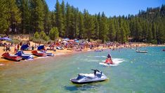 many people are on the beach with jet skis and jetskiing in the water