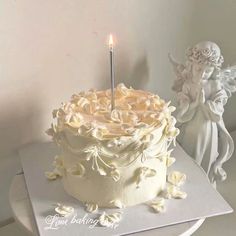 a white cake sitting on top of a table next to an angel figurine