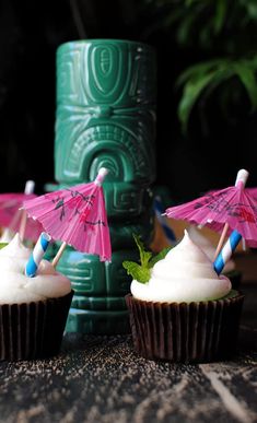 three cupcakes with pink and blue umbrellas sitting on top of each other