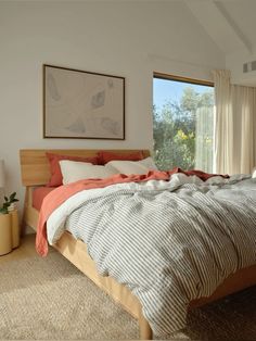 a large bed sitting in a bedroom next to a window covered in blankets and pillows