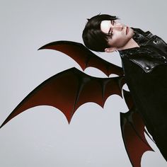 a man in black leather jacket with red bat wings on his chest and eyes closed