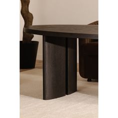 a black table with two legs in front of a white carpeted floor and a brown chair