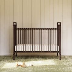 an empty crib in the corner of a room with white walls and green carpet