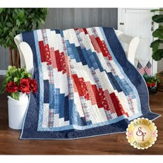 a red, white and blue quilt on a chair next to a potted plant