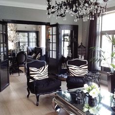 a living room filled with black furniture and a chandelier hanging from the ceiling