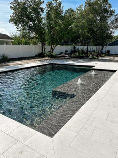 an empty pool in the middle of a backyard with water running through it and trees