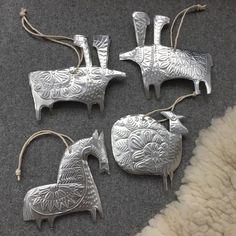 four silver ornaments are sitting on the floor next to a white rug and some fur