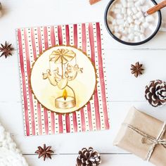 a christmas card with a candle on it next to some pine cones and cinnamons