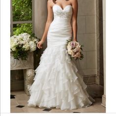 a woman in a white wedding dress standing next to a vase with flowers on it