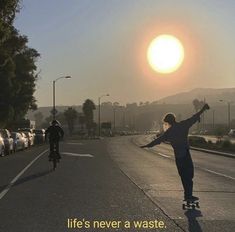 a man riding a skateboard down the side of a road next to a traffic filled street