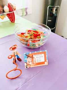 there is a bowl of gummy bears and a toy man on the table