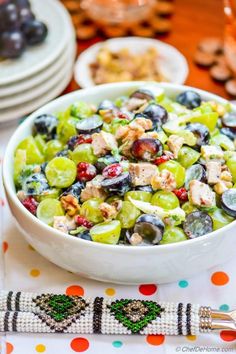 a white bowl filled with fruit and nuts on top of a table next to plates