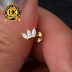 a person's hand holding a gold ring with two small white diamonds on it