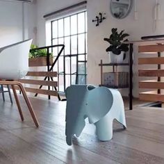 an elephant statue sitting on top of a hard wood floor next to a white table