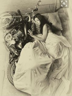 a woman laying in bed next to a motorcycle