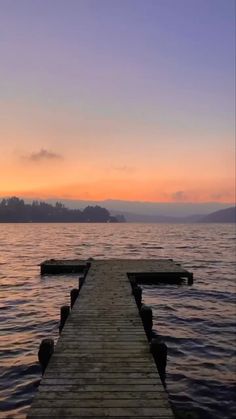 a wooden dock extending into the water at sunset