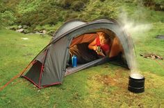 a woman sitting in a tent on top of a lush green field