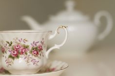 a white tea cup and saucer with pink flowers on it