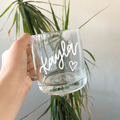 a person holding up a glass with the word kasey written on it in white ink