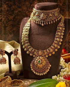 an assortment of jewelry on display in front of a mannequin and flower arrangement