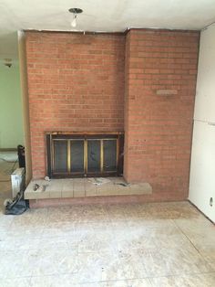 an empty living room with a fireplace in the middle and no one around it on the floor