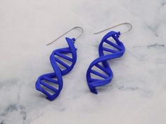 two blue earrings with the shape of a double - stranded spiral are on a marble surface