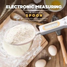 an electronic measuring device sitting on top of a wooden table next to eggs and flour