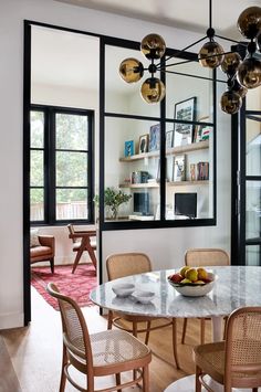 a dining room table with chairs and a bowl of fruit on it