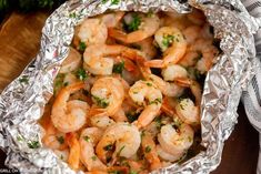 cooked shrimp in foil with parsley and pepper on the side, ready to be eaten