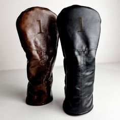 two black and brown leather mittens sitting next to each other on a white surface