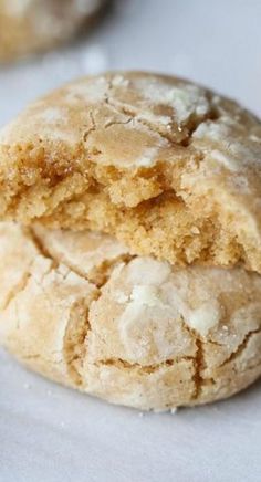 a close up of two cookies on a white tablecloth with other cookies in the background