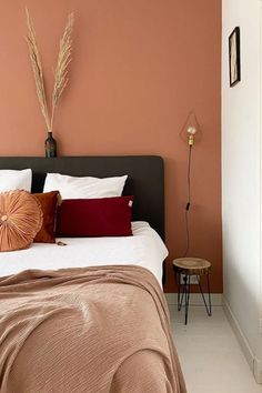 a bed with pillows and blankets in a room that is painted peach, brown and white