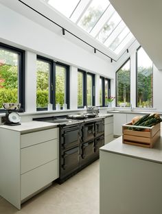 a kitchen with an oven, sink and counter tops in front of two large windows