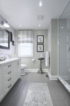 a white bathroom with gray tile flooring and walls, along with a walk in shower