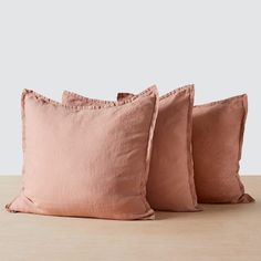 three pink pillows on a wooden table