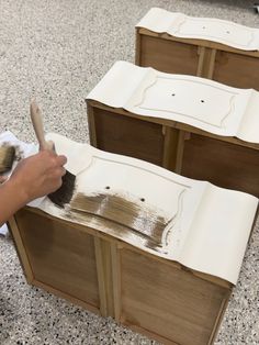 a person is painting some wooden furniture with a paintbrush and brush on the floor