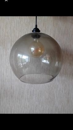 a clear glass light hanging from a ceiling in a room with beige walls and carpet