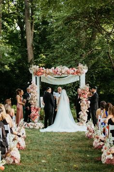 a bride and groom standing under an arch with flowers on it at the end of their wedding ceremony