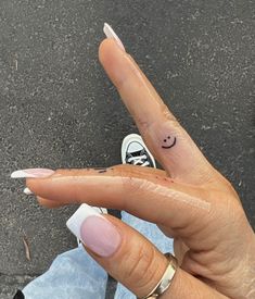 a person's hand with a smiley face tattoo on their thumb and the finger