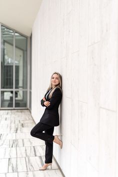 a woman leaning up against a wall with her legs crossed and arms on the side